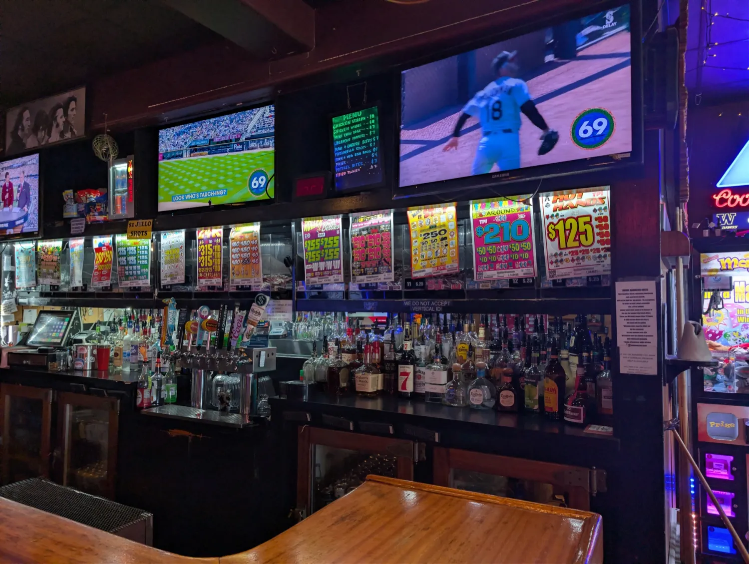 The bar at The Fireplace — taps, full liquor shelf, pull tabs, and the game on