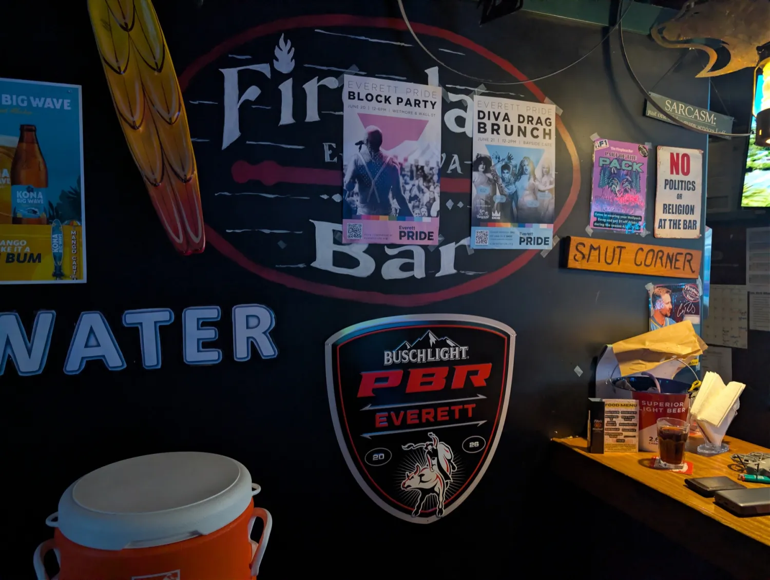 The Fireplace Bar wall with hand-painted logo, Everett Pride posters, and tin signs